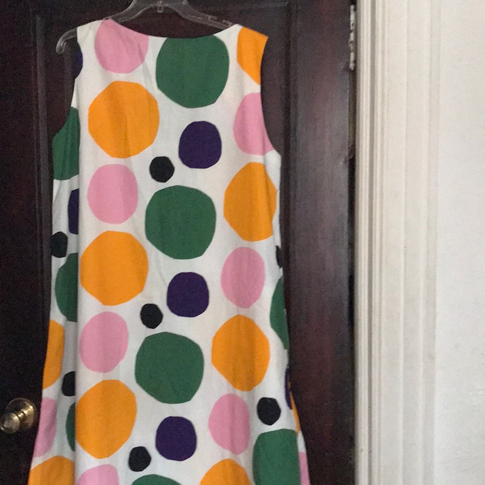 Sleeveless dress with large multicolored dots on a white background.